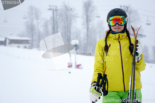 Image of Female skier standing with skies in one hand on background beautiful mountain landscape