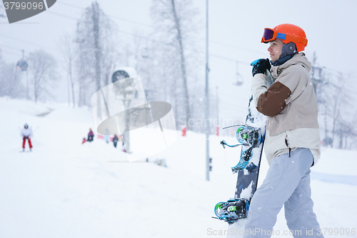 Image of Men snowboarder standing with snowboard and looking at beautiful mountain landscape