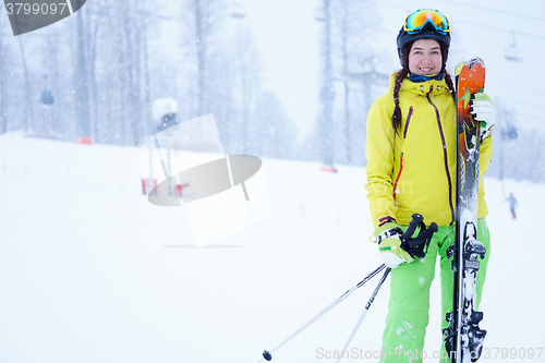 Image of Female skier standing with skies in one hand on background beautiful mountain landscape