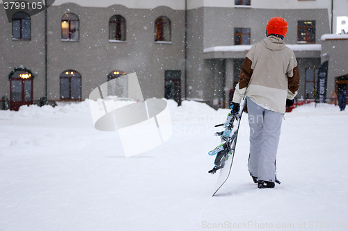 Image of Taired man snowboarder with snowboard in one hand coming back in hotel.