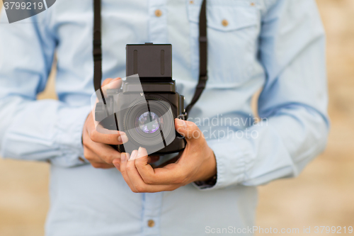 Image of close up of hipster man with film camera in city