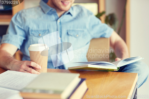 Image of happy student reading book and drinking coffee
