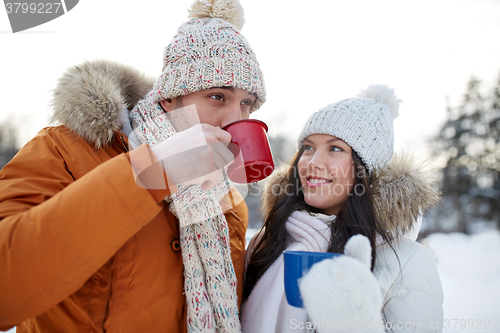 Image of happy couple with tea cups over winter landscape