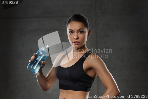 Image of woman drinking water from bottle in gym