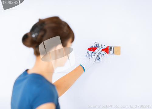 Image of woman with paintbrush colouring the wall