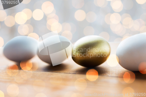 Image of close up of golden and white easter eggs on wood