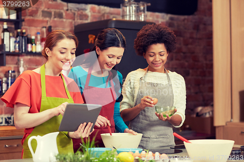 Image of happy women with tablet pc cooking in kitchen