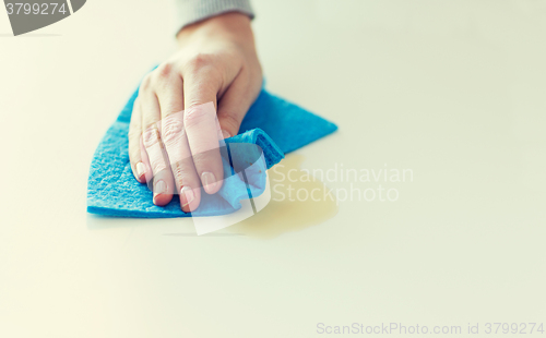 Image of close up of hand cleaning table surface with cloth