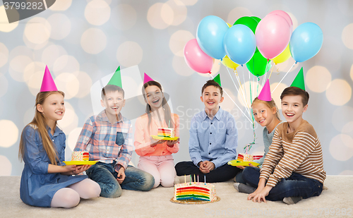 Image of happy children in party hats with birthday cake