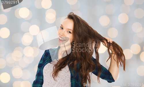 Image of happy teenage girl holding strand of her hair