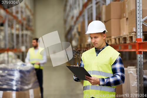 Image of man with clipboard in safety vest at warehouse