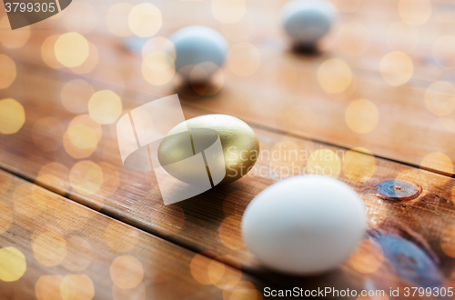 Image of close up of golden and white easter eggs on wood