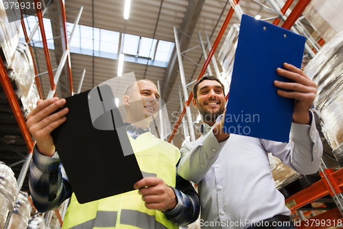 Image of worker and businessmen with clipboard at warehouse