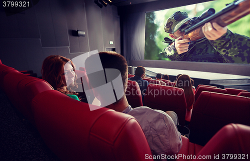 Image of happy couple watching movie and talking in theater