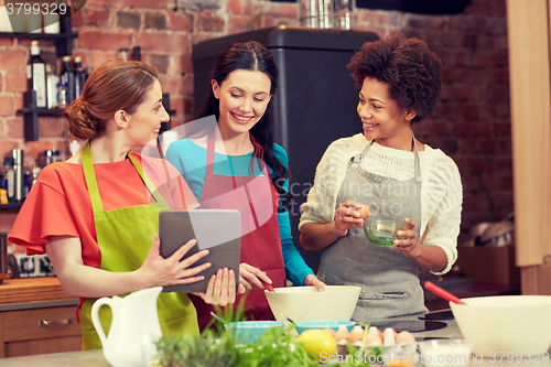 Image of happy women with tablet pc cooking in kitchen