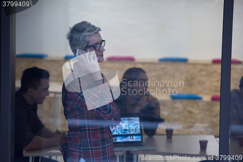 Image of business woman in meeting room  speaking by cell phone