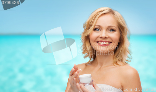 Image of happy middle aged woman with cream jar over sea