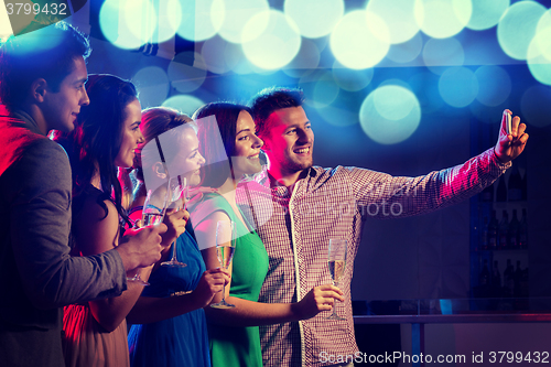 Image of friends with glasses and smartphone in club