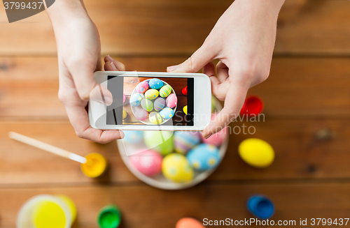 Image of close up of hands with easter eggs and smartphone