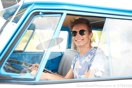 Image of smiling young hippie man driving minivan car