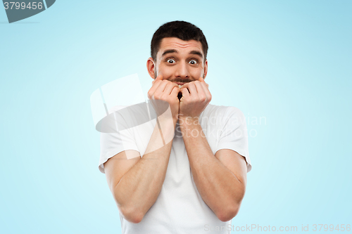 Image of scared man in white t-shirt over blue background