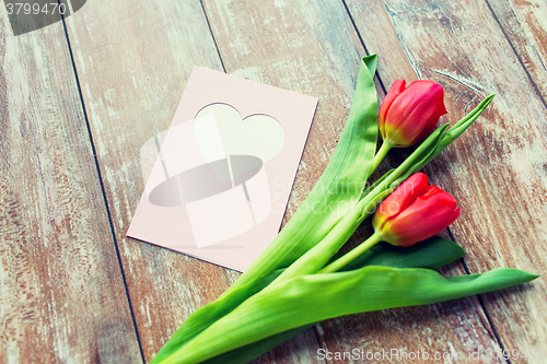 Image of close up of tulips and greeting card with heart