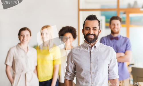 Image of happy young man over creative team in office