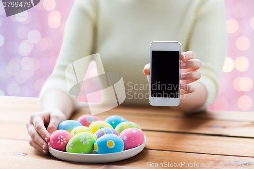 Image of close up of hands with easter eggs and smartphone