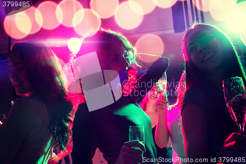 Image of smiling friends with glasses of champagne in club