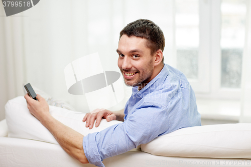 Image of happy man with smartphone at home