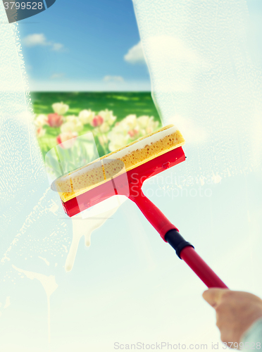 Image of close up of hand cleaning window with sponge