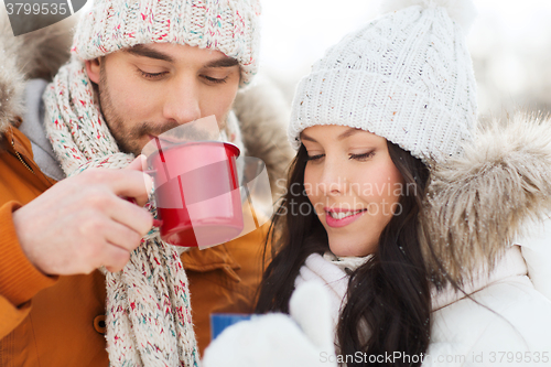 Image of happy couple with tea cups over winter landscape