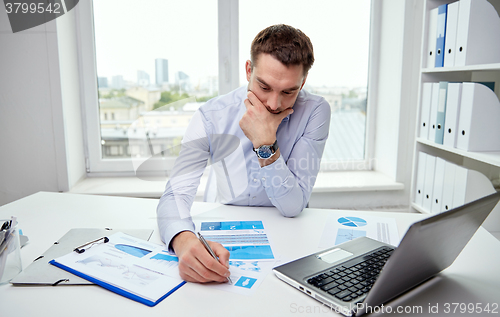 Image of stressed businessman with papers in office