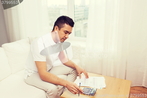 Image of man with papers and calculator at home