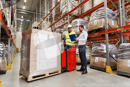 Image of worker on forklift and businessman at warehouse