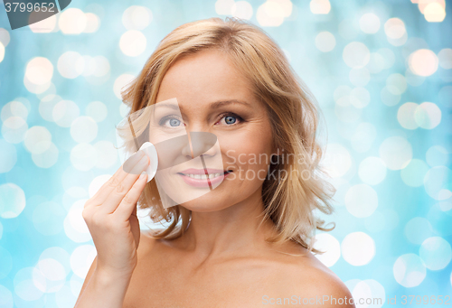 Image of happy woman cleaning face with cotton pad