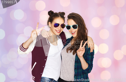 Image of smiling teenage girls in sunglasses showing peace