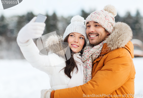 Image of happy couple taking selfie by smartphone in winter