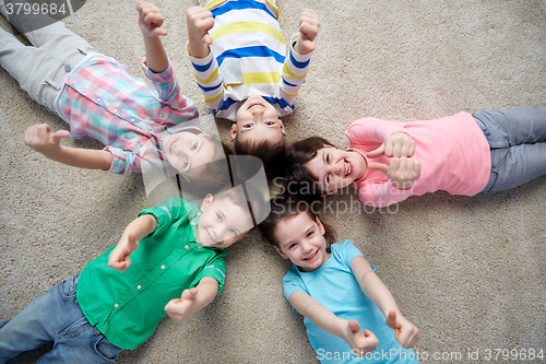 Image of happy kids lying on floor and showing thumbs up