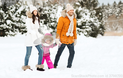 Image of happy family in winter clothes walking outdoors