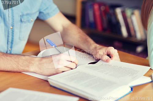 Image of close up of student hands writing to notebook