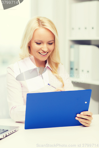 Image of smiling businesswoman with clipboard in office