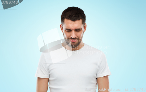 Image of unhappy young man over blue background