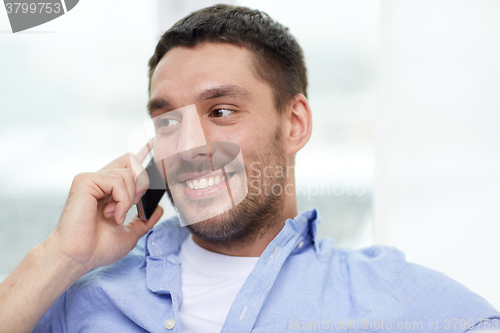 Image of happy man calling on smartphone at home