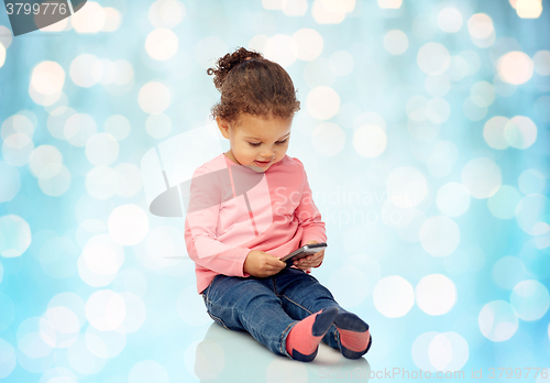 Image of smiling little baby girl playing with smartphone