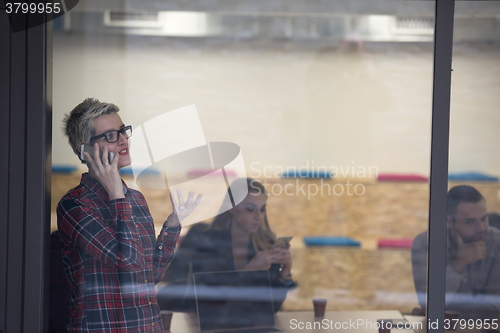 Image of business woman in meeting room  speaking by cell phone