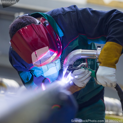 Image of Industrial worker welding in metal factory.