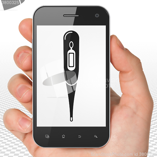 Image of Medicine concept: Hand Holding Smartphone with Thermometer on display