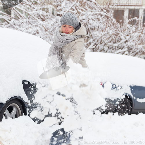 Image of Independent woman shoveling snow in winter.