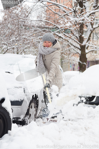 Image of Independent woman shoveling snow in winter.